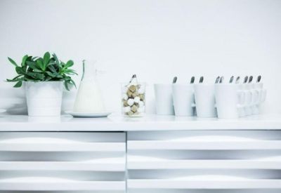 Close-up of a white refreshment station with a green potted plant and coffee supplies.