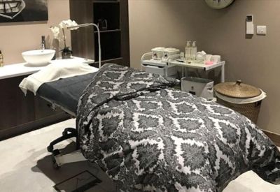 Private spa treatment room with a massage table and patterned throw.