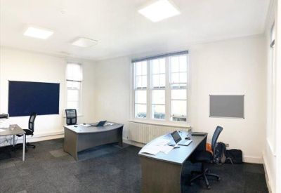 Private two-person office suite with grey desks, blue chairs, and a large window.