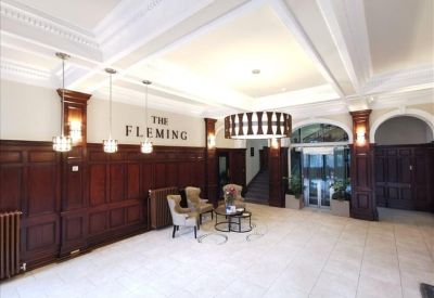 Grand lobby featuring dark wood paneling, a marble floor, and traditional wingback chairs.