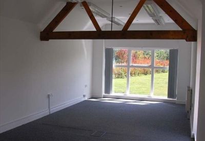 Bright open-plan office featuring vaulted ceilings with exposed timber beams and garden views.