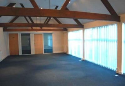 Spacious meeting room with dark blue carpeting, timber rafters, and vertical window blinds.