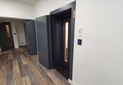 Office corridor with dark wood flooring and modern lift entrance.