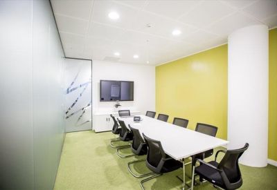Professional boardroom with a long white table, black chairs, and a feature lime green wall.