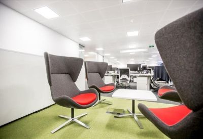 Modern lounge area with stylish grey and red high-back chairs on green flooring.
