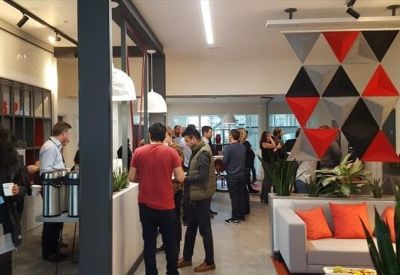 Vibrant communal lounge with orange sofa, patterned wall art, and coffee station.
