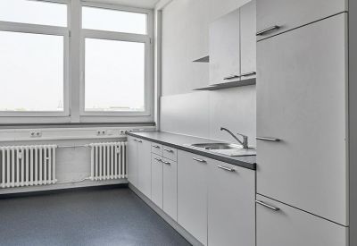 Bright white communal kitchen area with modern cabinetry and a large window.