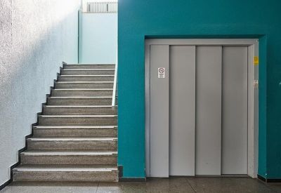 Clean interior hallway featuring a grey elevator door and a blue accent wall next to a staircase.