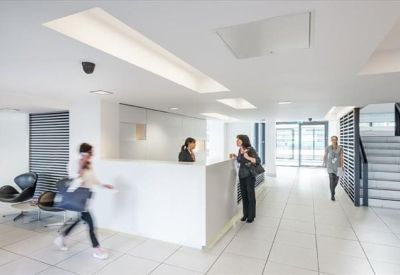 Bright, minimalist reception area with a white front desk and modern staircase.