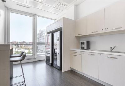 Modern office kitchenette area with white cabinetry and vending machines.