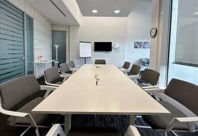 Minimalist white reception desk area with wooden flooring and bright lighting.