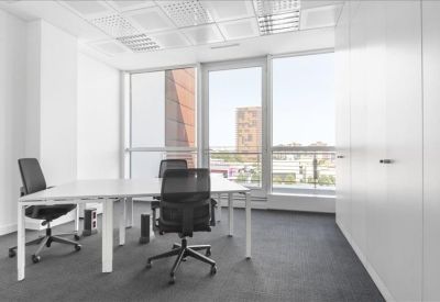 Bright corner office with two desks and view of surrounding city buildings.