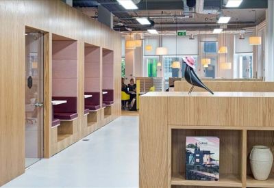 Communal breakout area featuring private wooden booths with purple seating and a decorative bird sculpture.