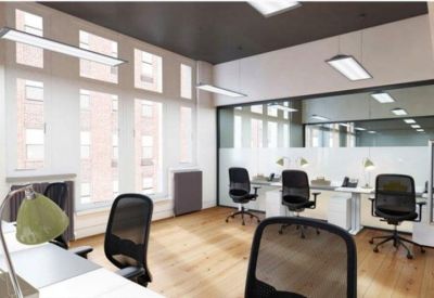 Bright open-plan office with black mesh chairs, light wood floors, and large windows.