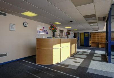 Bright reception area with a curved wooden desk and floral arrangement.