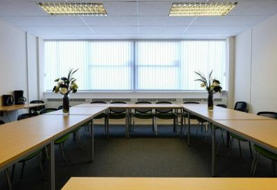 Professional meeting room with U-shaped table layout and large windows.