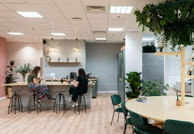 Communal kitchen and breakout area with a breakfast bar, wooden floors, and indoor plants.