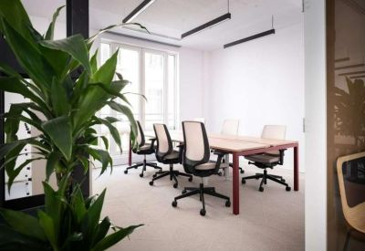 Modern meeting room with a light wood table, ergonomic chairs, and large windows.