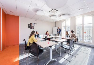 Team meeting in progress within a bright workspace featuring an orange accent wall.