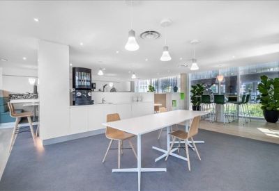 Modern breakout area with a white communal table and sleek kitchen facilities.