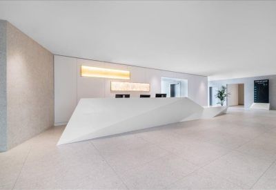 Minimalist reception area featuring a sharp-angled white front desk and warm wall lighting.