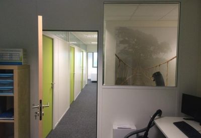 A hallway view through an open door showing lime green office doors.