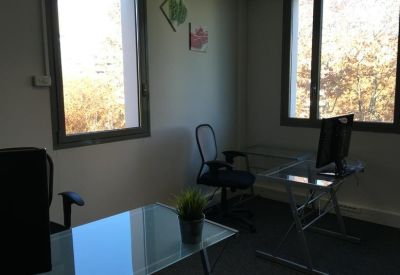 Dual workstation office suite with glass desks and large windows for natural light.