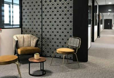 Breakout space with mid-century style chairs and a decorative patterned wall panel.