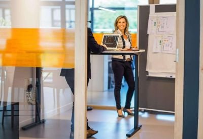 Professional at a height-adjustable standing desk in a bright office.