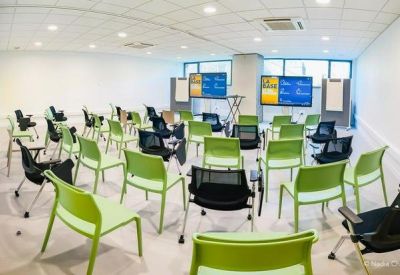 Flexible training room with green chairs and digital presentation screens.