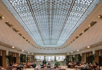 Symmetrical wide view of an expansive indoor atrium with a grand glass roof and perimeter seating.