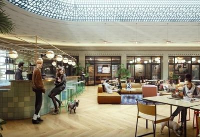 Open-plan coworking space with light wood floors and various seating arrangements near a kitchen bar.