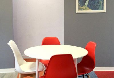 Small meeting area with round table and red chairs.