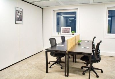 Modern workspace with back-to-back desks divided by light wood partitions.