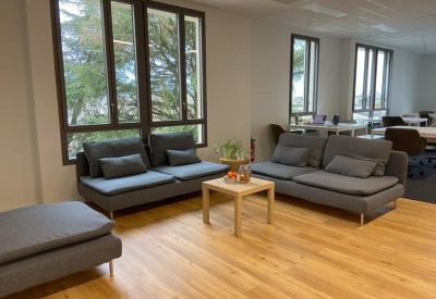 Inviting breakout area with grey sofas and light wood floors.