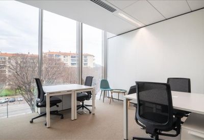Sunlit private office with two white desks and large windows.