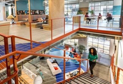 Spacious multi-level atrium office with central stairs and various meeting zones.