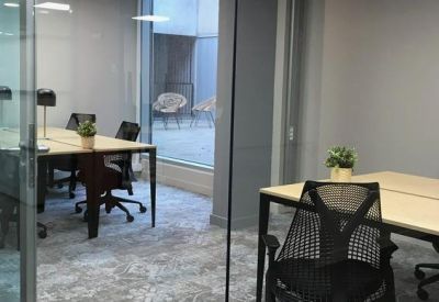 Glazed internal meeting room with a wooden table and black mesh chairs.