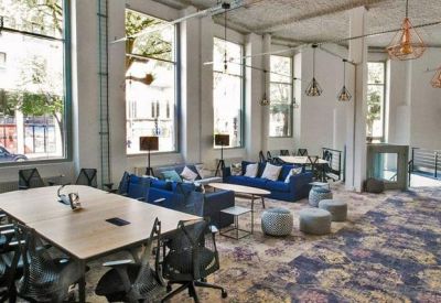 Spacious open-plan coworking area with high ceilings and various seating options.