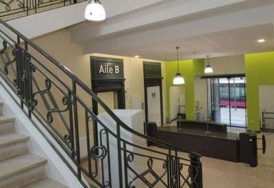 Bright reception lobby featuring a grand staircase with decorative iron railings.