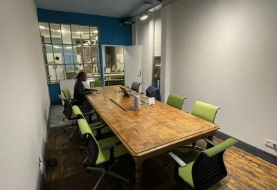 Spacious meeting room featuring a large wooden table and bright green ergonomic chairs.
