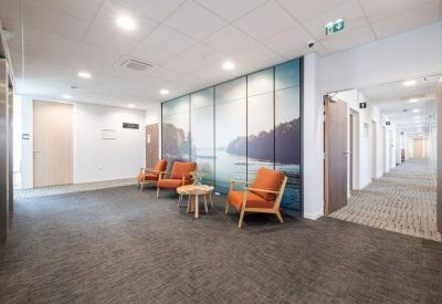 Modern lobby area with orange armchairs, a coffee table, and a large scenic wall mural.