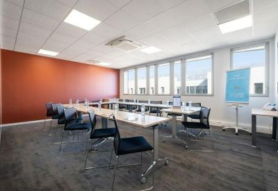 Meeting room with a U-shaped table setup, black chairs, and a warm terracotta feature wall.