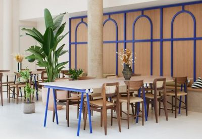 Bright workspace featuring a long communal table with blue legs and a decorative arched wood wall.