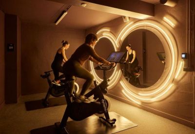 Modern fitness studio with indoor cycling bikes and unique circular neon light wall installations.