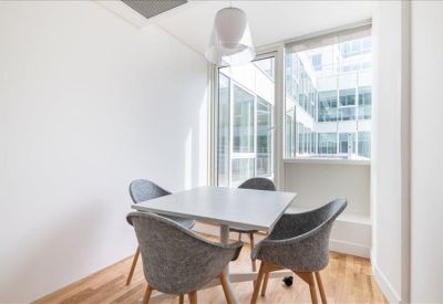 Small private meeting pod with grey upholstered chairs and light wood flooring.