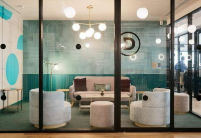 Bright glass-walled lounge area with plush armchairs and a modern sphere chandelier.