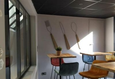 Cafe area with wooden tables, colorful chairs, and fork and spoon wall art.