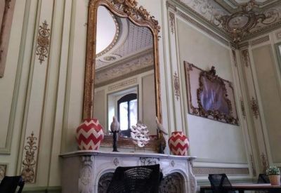 Elegant room with high ceilings, ornate mirror, and marble fireplace.