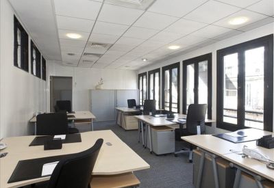 Open-plan office with multiple desks and natural light.